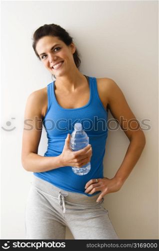 Portrait of woman in fitness attire holding water bottle and smiling.