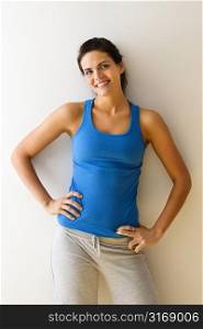 Portrait of woman in fitness attire smiling with hands on hips.