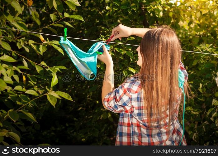 Portrait of woman in shirt drying bikini on clothesline