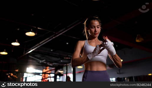 Portrait of woman learning Muay Thai to build up the strength of the body and use it for self-defense. Are using hand wraps before putting on boxing gloves for boxing