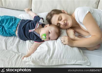 Portrait of woman lying with baby son on pillow