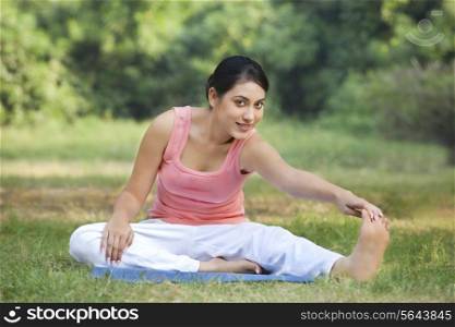 Portrait of woman on grass stretching