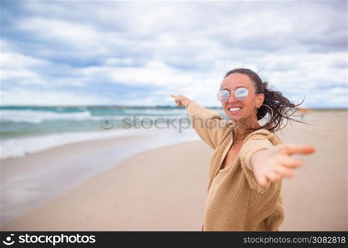 Portrait of woman on the beach on vacation in windy and cloudy weather. Young woman on the beach in the storm