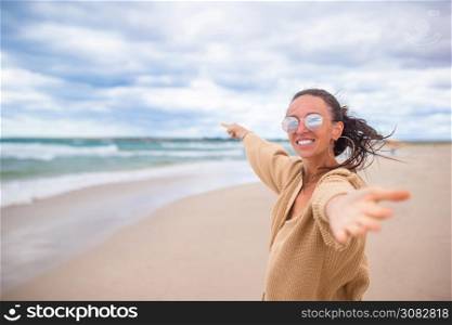 Portrait of woman on the beach on vacation in windy and cloudy weather. Young woman on the beach in the storm