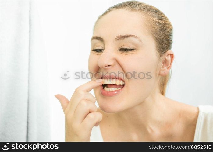 Portrait of woman picking food stuck in teeth with finger