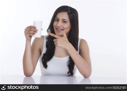 Portrait of woman pointing to glass of milk
