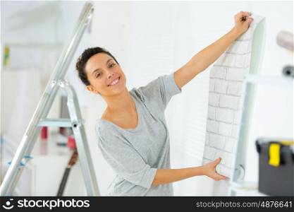 portrait of woman putting up wallpaper