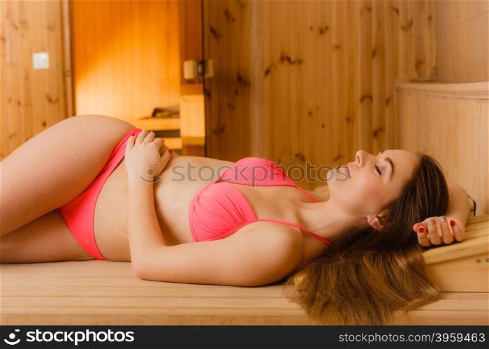 Portrait of woman relaxing in sauna. Spa wellbeing. Portrait of young woman relaxing in wooden finnish sauna. Attractive girl in bikini resting. Spa wellbeing pleasure.