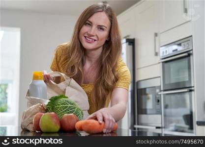 Portrait Of Woman Returning Home From Shopping Trip Unpacking Plastic Free Grocery Bags