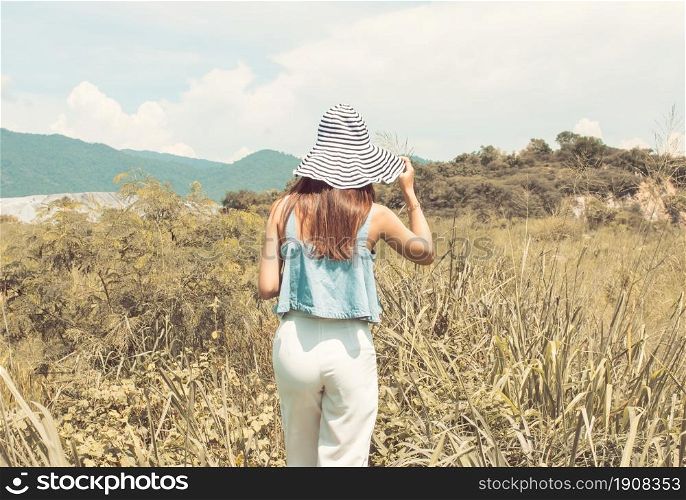 Portrait of woman&rsquo;s back wearing hat travel in summer time with background of blur mountains and blue sky