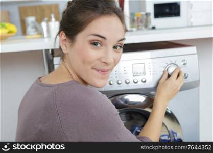 portrait of woman setting dial on her washing machine