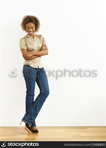 Portrait of woman standing against white wall smiling.