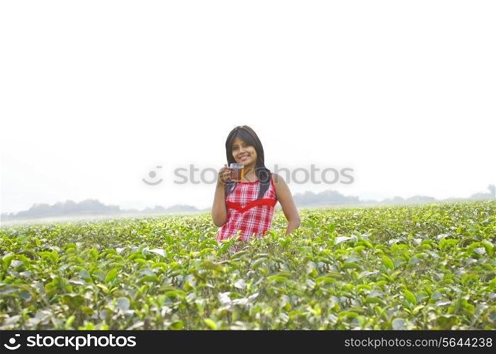 Portrait of woman standing in tea plantation with a cup of tea