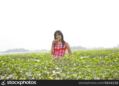 Portrait of woman standing in tea plantation with a cup of tea