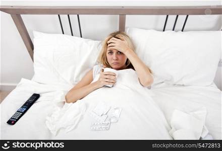 Portrait of woman suffering from cold having coffee in bed