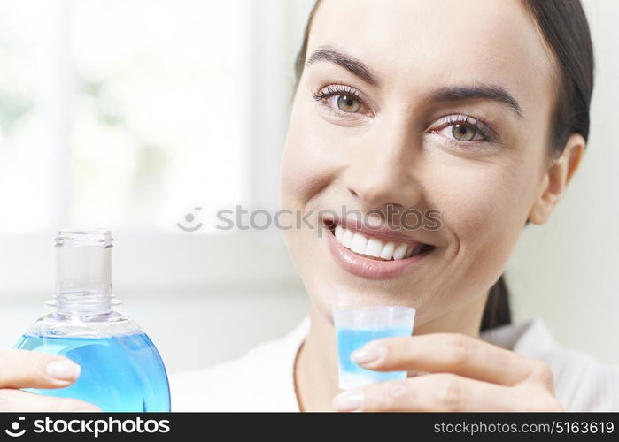 Portrait Of Woman With Beautiful Teeth Using Mouthwash In Bathroom