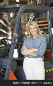 Portrait Of Woman With Fork Lift Truck In Warehouse