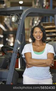 Portrait Of Woman With Fork Lift Truck In Warehouse