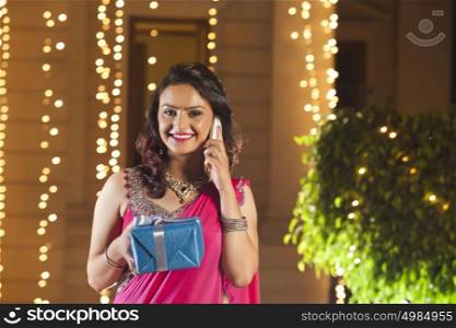 Portrait of woman with gift talking on mobile phone