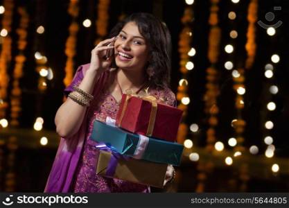 Portrait of woman with gifts talking on mobile phone
