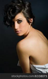 Portrait of woman with intense look on black background, nude shoulder. Studio portrait