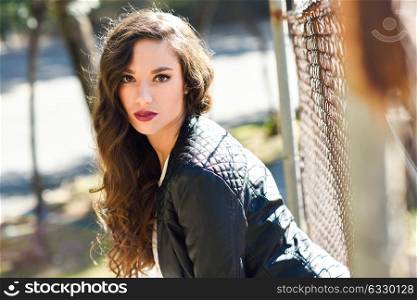 Portrait of woman with long hair wearing leather jacket in urban background