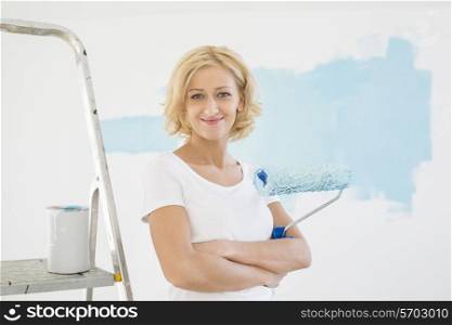 Portrait of woman with paint roller in new house