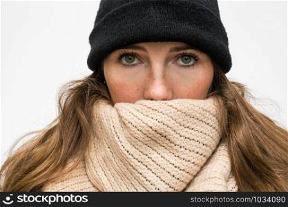 Portrait of woman wrapped in winter had and scarf, winter woolen wearing looking cold closeup. Portrait of woman wrapped in winter had and scarf, winter woolen wearing looking cold