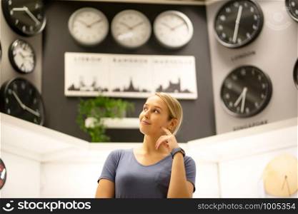 portrait of women looking away while standing against clocks on wall