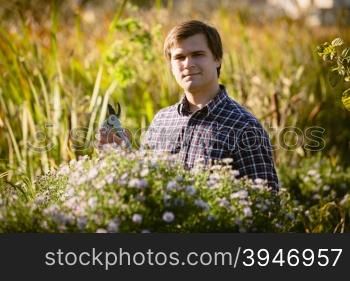 Portrait of working young gardener posing at flowerbed