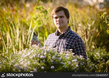 Portrait of working young gardener posing at flowerbed