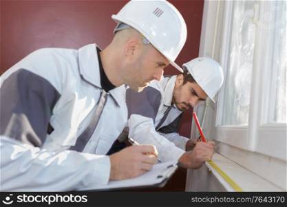 portrait of workmen measuring window