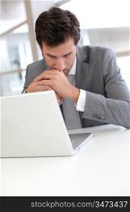 Portrait of worried businessman in front of laptop