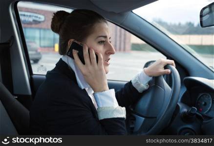 Portrait of worried businesswoman driving car and talking by phone