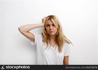 Portrait of worried woman with hand in hair against white background
