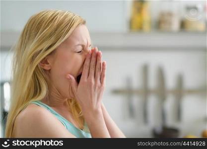 Portrait of yawing young woman in the morning in kitchen