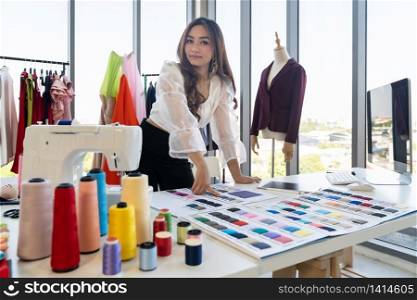 Portrait of young adult asian fashion designer working from home with colour palette as owner entrepreneur at her atelier studio. Using for entrepreneur Small Business startup concept.
