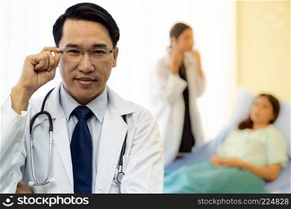 Portrait of Young adult Doctor with nurse and Patient in background.