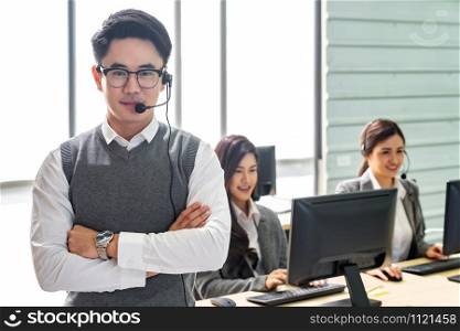 Portrait of Young adult friendly and confidence operator man with headsets and his team working in a call center as customer service and technical support.