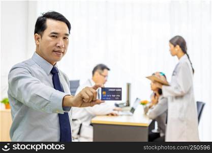 Portrait of Young adult Patient with credit card with examination room medical office background for insurance concept