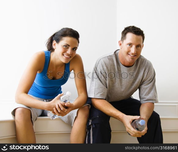 Portrait of young adult woman and man sitting wearing active wear.