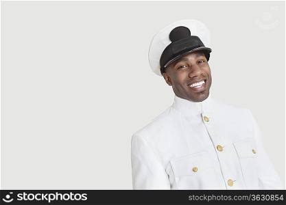 Portrait of young African American Navy officer smiling against gray background