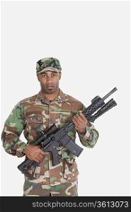 Portrait of young African American US Marine Corps soldier with M4 assault rifle over gray background