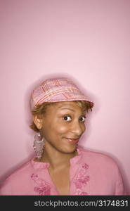 Portrait of young African-American woman on pink background with comical expression on her face.