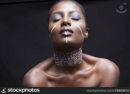 Portrait of young african american woman with traditional white paint on face 
