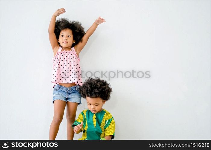 Portrait of young african girl stand behind the boy with white background and show different actions.