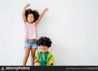 Portrait of young african girl stand behind the boy with white background and show different actions.