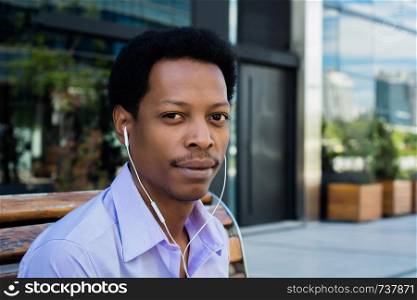 Portrait of young Afro American businessman with earphones in the city.