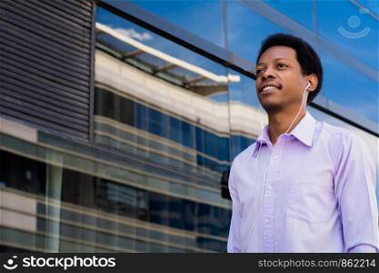 Portrait of young Afro American businessman with earphones in the city.