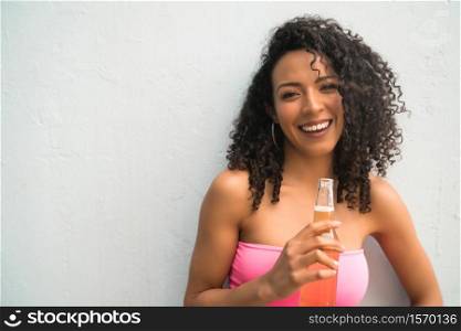 Portrait of young Afro american latin woman enjoying and drinking a bottle of beer. Lifestyle concept.